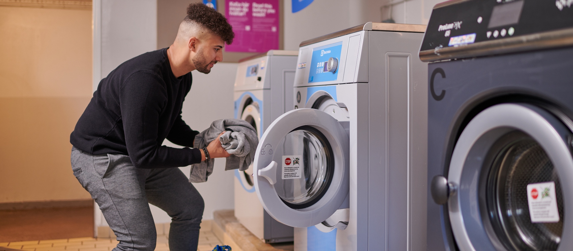 Manlig student stoppar in tvätt i tvättmaskinen
