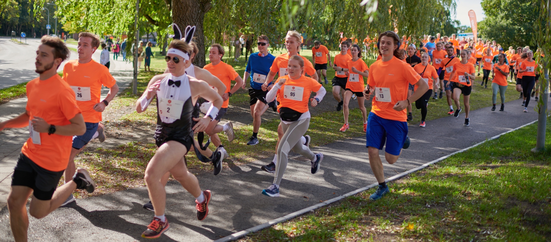 A group of people running in orange t-shirts. Some are dressed up like a bunny